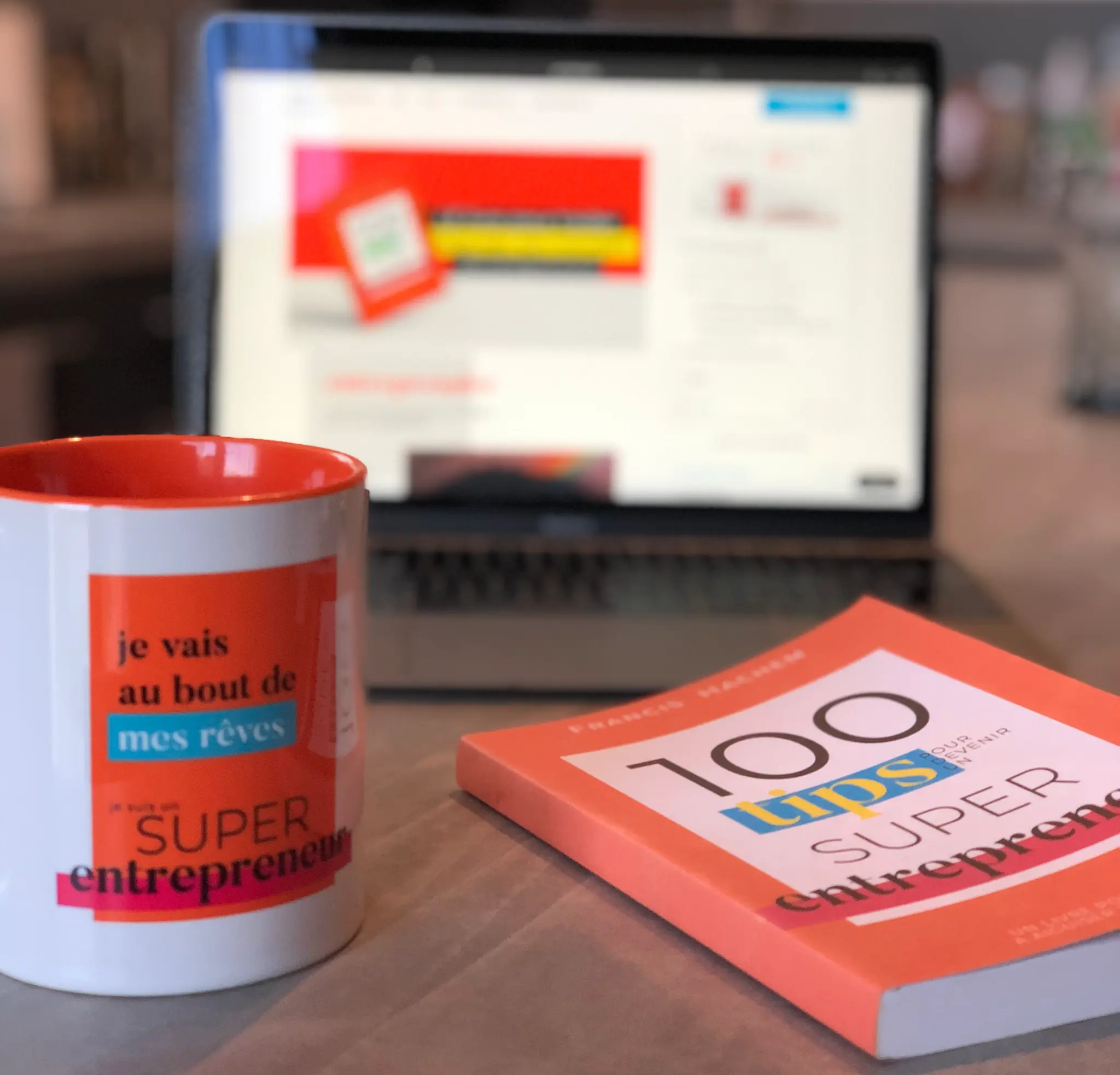100 Tips book, mug and laptop on a desk